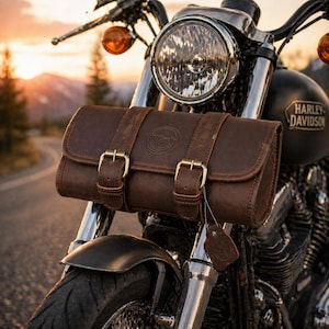 Könnte beinhalten: Braune Motorrad-Lenkertasche aus Leder mit zwei Riemen und goldenen Schnallen. Die Tasche ist an einem Harley Davidson-Motorrad montiert. Auf der Tasche ist der Text "V Craft" geprägt.