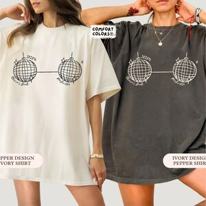 May include: Two oversized t-shirts, one ivory and one pepper, with a graphic of two disco balls linked by a line. The text "2625a", "Olivia's Bach", and "Nashville" are printed on the shirts. The shirts are part of the Comfort Colors collection.