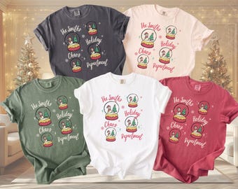 May include: Five short-sleeve crew neck t-shirts in charcoal, light pink, olive green, white, and red. Each shirt features a graphic of four snow globes with snowmen and trees, with the text "The Smiths Holiday Chaos Department" printed.
