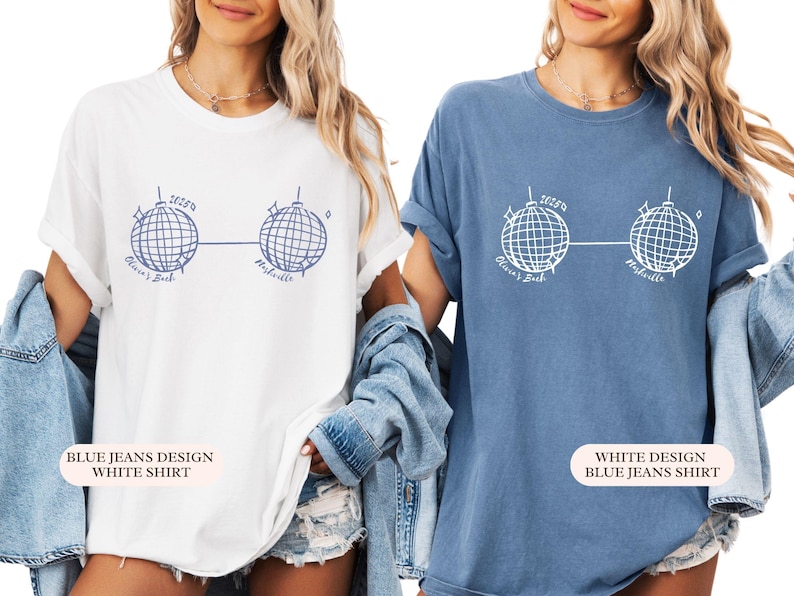 May include: Two t-shirts, one white and one blue, each with a graphic of two disco balls linked by a line. The text "Olivia's Bach Nashville" is printed below. The white shirt has a blue design, and the blue shirt has a white design. The shirts are casual wear.