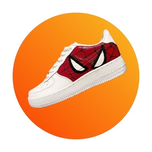 Puede incluir: Zapatillas blancas de ca&ntilde;a baja con un dise&ntilde;o de Spiderman rojo y negro en el lateral. El dise&ntilde;o presenta los ojos de Spiderman y un patr&oacute;n de telara&ntilde;a.