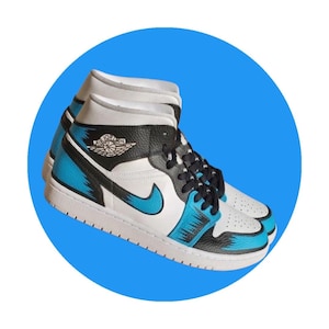 May include: Pair of high-top sneakers with a white base, black accents, and vibrant blue details. Features the iconic swoosh logo and the Air Jordan logo on the side. The shoes have a white sole and black laces.