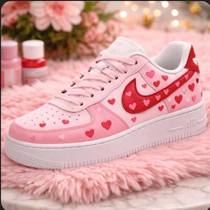 Pu&ograve; includere: Sneakers Air Force 1 rosa e rosse con design a cuore. Le sneakers hanno una suola bianca e un logo Nike rosso con dettagli a cuore. La scarpa &egrave; decorata con piccoli cuori rossi e rosa.
