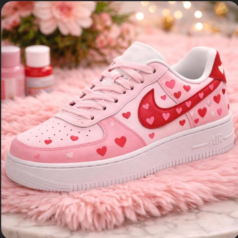 Pu&ograve; includere: Sneakers Air Force 1 rosa e rosse con design a cuore. Le sneakers hanno una suola bianca e un logo Nike rosso con dettagli a cuore. La scarpa &egrave; decorata con piccoli cuori rossi e rosa.