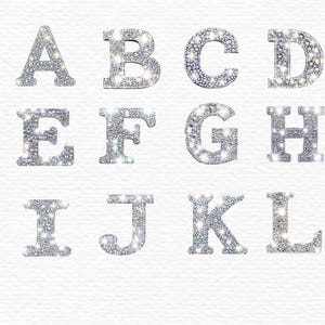 Pu&ograve; includere: Lettere dell'alfabeto in glitter argentato, dalla A alla L, su sfondo bianco.