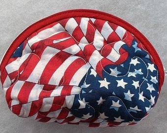 Könnte beinhalten: Eine rote, weiße und blaue Stofftasche mit Reißverschluss. Die Tasche ist mit einem gesteppten amerikanischen Flaggenmuster verziert.