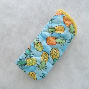 May include: A blue quilted hot pad with a yellow border and a pineapple pattern.