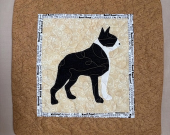 Könnte beinhalten: Ein quadratischer, gesteppter Tischset mit Hundemotiv. Die Mitte zeigt eine schwarz-weiße Boston Terrier-Silhouette auf cremefarbenem Hintergrund mit einem Wirbelmuster. Der Rand ist ein brauner Stoff mit sich wiederholendem Textmuster.