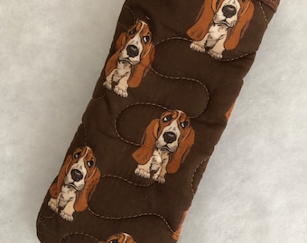 Puede incluir: Manopla de horno acolchada marrón con un patrón de perros sabueso. La manopla tiene un tejido acolchado marrón con un ribete marrón.