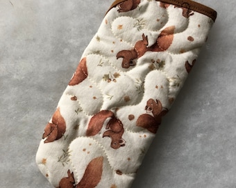 Könnte beinhalten: Ein weißer, gesteppter Ofenhandschuh mit braunem Besatz. Der Handschuh zeigt ein sich wiederholendes Muster aus braunen Eichhörnchen und Blättern.