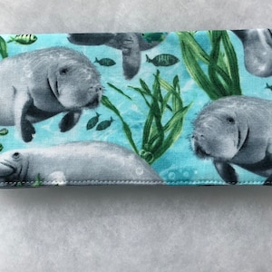 May include: A blue fabric checkbook cover with a repeating pattern of manatees, seaweed, and fish.