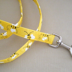 Peut inclure: Une laisse de chien jaune avec un motif d'abeille et un mousqueton argenté.