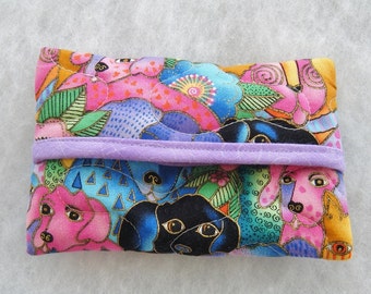 Puede incluir: Un colorido porta pañuelos de tela con un patrón repetido de perros estilizados, flores y hojas en rosa, azul y dorado. El soporte tiene una solapa lavanda y está acolchado.