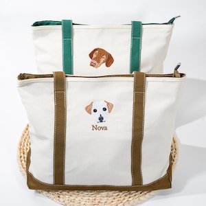 May include: Two canvas tote bags with embroidered dog portraits. The top bag has a green handle and a brown dog portrait. The bottom bag has brown handles and a white dog portrait with the name "Nova" embroidered below.