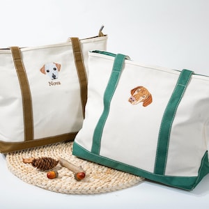 May include: Two white canvas tote bags with embroidered dog portraits. One bag has brown accents and the name "Nova" embroidered below the dog. The other bag has green accents. Both bags have sturdy handles and a zippered top.