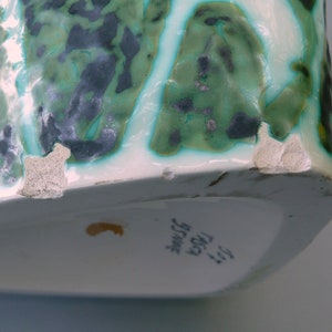 Puede incluir: Un jarr&oacute;n de cer&aacute;mica blanca con un patr&oacute;n abstracto verde y negro. El jarr&oacute;n tiene un borde astillado y el texto "317 TRISA  JUGEND  SWISS" en la parte inferior.