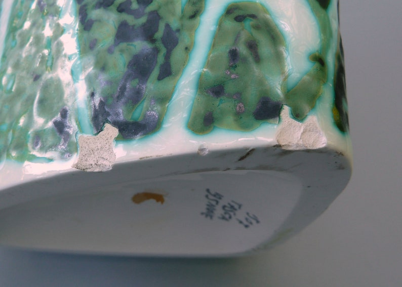 Puede incluir: Un jarr&oacute;n de cer&aacute;mica blanca con un patr&oacute;n abstracto verde y negro. El jarr&oacute;n tiene un borde astillado y el texto "317 TRISA  JUGEND  SWISS" en la parte inferior.