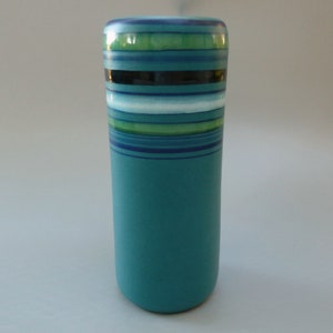 May include: A teal ceramic vase with a striped design in shades of blue, green, and white.
