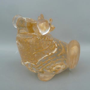 May include: A gold glass sculpture of a frog with a textured surface and small air bubbles. The frog is sitting on its hind legs with its front legs raised.