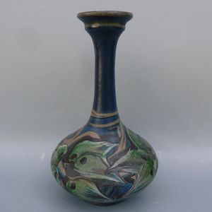 May include: A blue ceramic vase with a narrow neck and a wide, rounded base. The vase is decorated with a stylized design of green and brown fish.