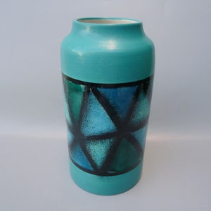May include: A turquoise ceramic vase with a geometric pattern of black and blue triangles.