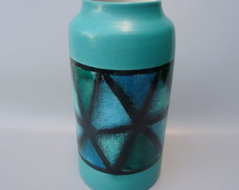 May include: A turquoise ceramic vase with a geometric pattern of black and blue triangles.
