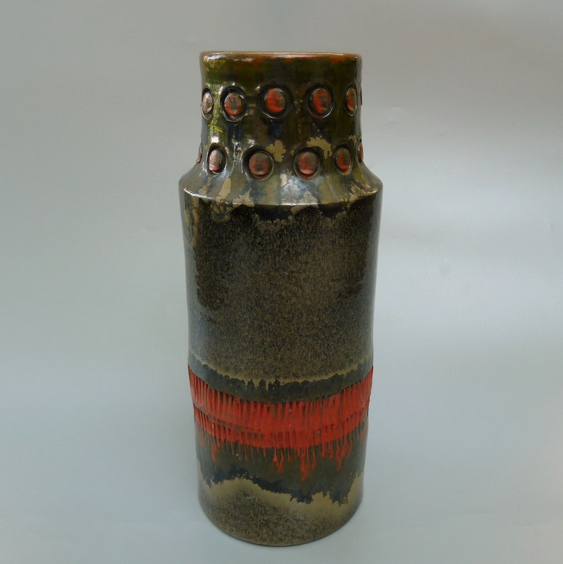 May include: A dark green ceramic vase with a red band and a row of orange circles around the top.