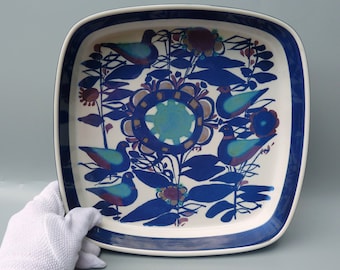 May include: Square ceramic serving dish with a blue and white floral design featuring stylized birds. The dish has a blue rim.