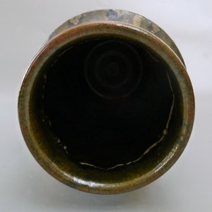 May include: The inside of a green glazed ceramic pot with a dark brown rim. The pot has a white glaze line around the top edge.