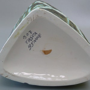 Puede incluir: La parte inferior de un jarr&oacute;n de cer&aacute;mica triangular con un patr&oacute;n abstracto verde y blanco. El jarr&oacute;n est&aacute; marcado con el texto "1507 TASCA 1957 NOVE".