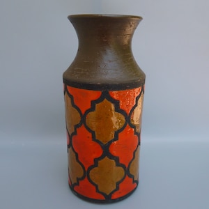 May include: A brown ceramic vase with a geometric pattern in orange and brown. The vase has a wide mouth and a narrow base.