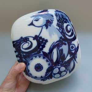 May include: A white ceramic square dish with a blue and white stylized bird design. The bird is surrounded by blue and white floral patterns.