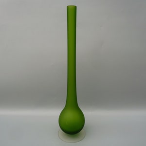 May include: A tall, green glass vase with a rounded base and a slender neck. The vase is frosted and has a clear glass base.