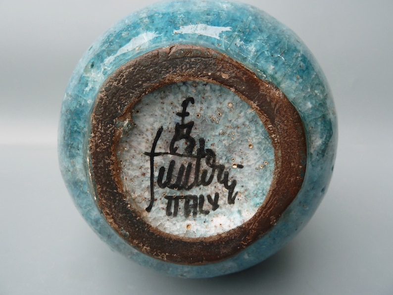 Może przedstawiać: Sp&oacute;d turkusowego wazonu ceramicznego z brązową krawędzią. Wazon jest oznaczony tekstem "F.B. Fulviery ITALY".