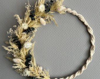 May include: A cream-colored macrame wreath with dried pampas grass, white flowers, and eucalyptus leaves.
