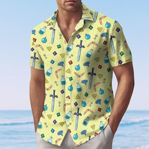 May include: Short-sleeved button-down shirt with a light yellow background and a repeating pattern of cartoon swords, bottles, boomerangs, keys, and gems. The shirt has a classic collar and is worn open.