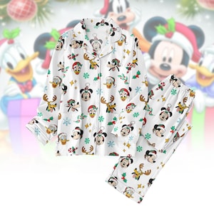 May include: White Christmas-themed pajama set featuring Mickey Mouse, Donald Duck, and Pluto. The long-sleeved top and pants are covered in festive character prints, snowflakes, and holly. The pajama set has a button-down top with a chest pocket.