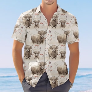 May include: Short-sleeved button-down shirt with a repeating pattern of Highland cows, butterflies, and floral accents on a cream background. The shirt features a classic collar and a relaxed fit, perfect for casual wear.