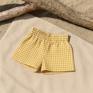 May include: Yellow and white gingham shorts with a gathered elastic waistband.