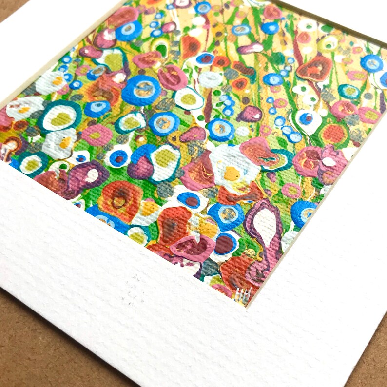 May include: Abstract painting with a colorful, swirling pattern of blue, green, yellow, red, and white. The painting is framed in a white mat.