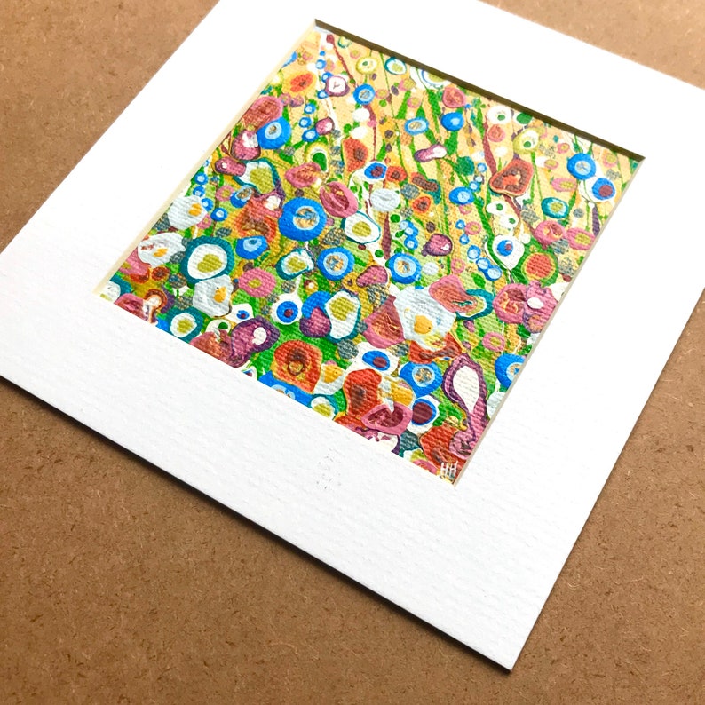 May include: A colorful abstract painting with a variety of shapes and colors, including blue, green, yellow, red, and white. The painting is framed in a white mat.