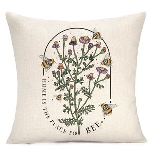 a white pillow with a picture of a plant and bees on it