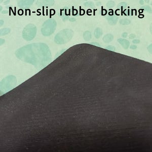 May include: Close-up of a black non-slip rubber backing on a light green surface with a paw print pattern. The text "Non-slip rubber backing" is visible at the top of the image.