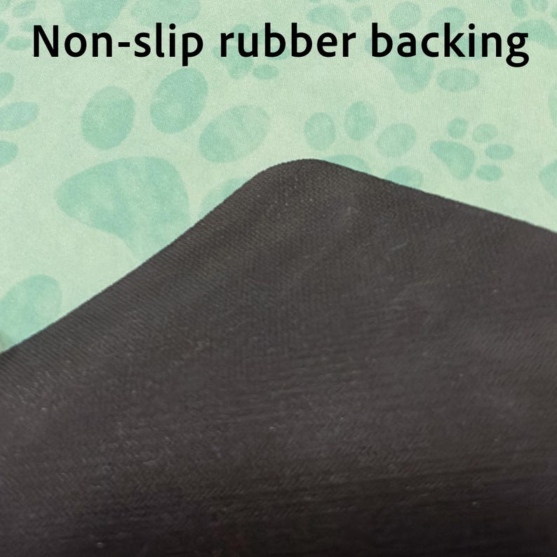 May include: Close-up of a black non-slip rubber backing on a light green surface with a paw print pattern. The text "Non-slip rubber backing" is visible at the top of the image.