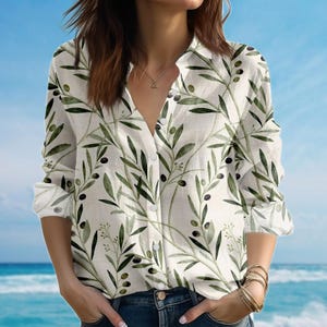 Può includere: Camicia bianca con bottoni con un motivo a ramo di ulivo verde. La camicia a maniche lunghe presenta un colletto classico e polsini con bottoni. Il design del ramo di ulivo include foglie verdi e olive nere.