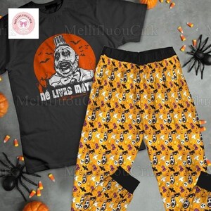 May include: Black Halloween pajama set featuring a graphic of a man in a top hat with the text "No Lives Mat" on the black t-shirt. The pajama pants are yellow with a repeating pattern of ghosts, bats, and pumpkins. The set is designed for Halloween.