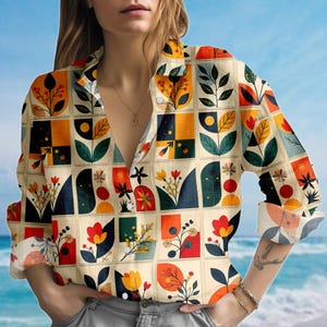 May include: A button-down shirt with a colorful floral pattern. The shirt features a beige background with square blocks containing stylized flowers and leaves in red, orange, yellow, and blue. The sleeves are rolled up, revealing a patterned cuff.