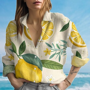 May include: A lemon-print shirt with a beige background. The shirt features large yellow lemons, green leaves, and small white flowers. The sleeves are rolled up, showing a yellow interior. The shirt has a button-down design.