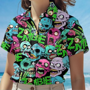 May include: Black button-up shirt with a colorful zombie-themed pattern. The design features multiple zombie faces in shades of pink, blue, and purple, with the word "ZOMBIE" in green. The shirt has short sleeves.