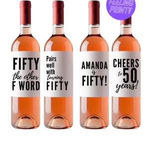 May include: Four bottles of rosé wine with custom labels. The labels feature phrases like "FIFTY the other F WORD", "Pairs well with turning FIFTY", "AMANDA is FIFTY!", and "CHEERS to 50 years!". Each bottle has a burgundy cap.